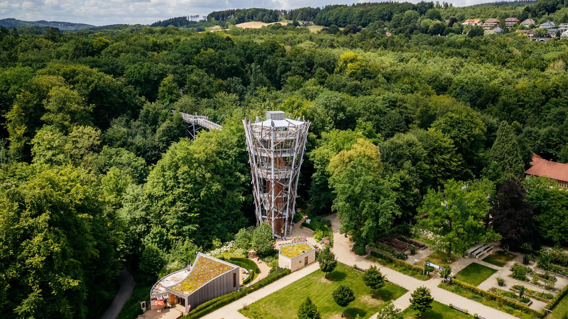 Aussichtsturm im Wald mit verschlungenen Pfaden und umgebender grüner Landschaft.