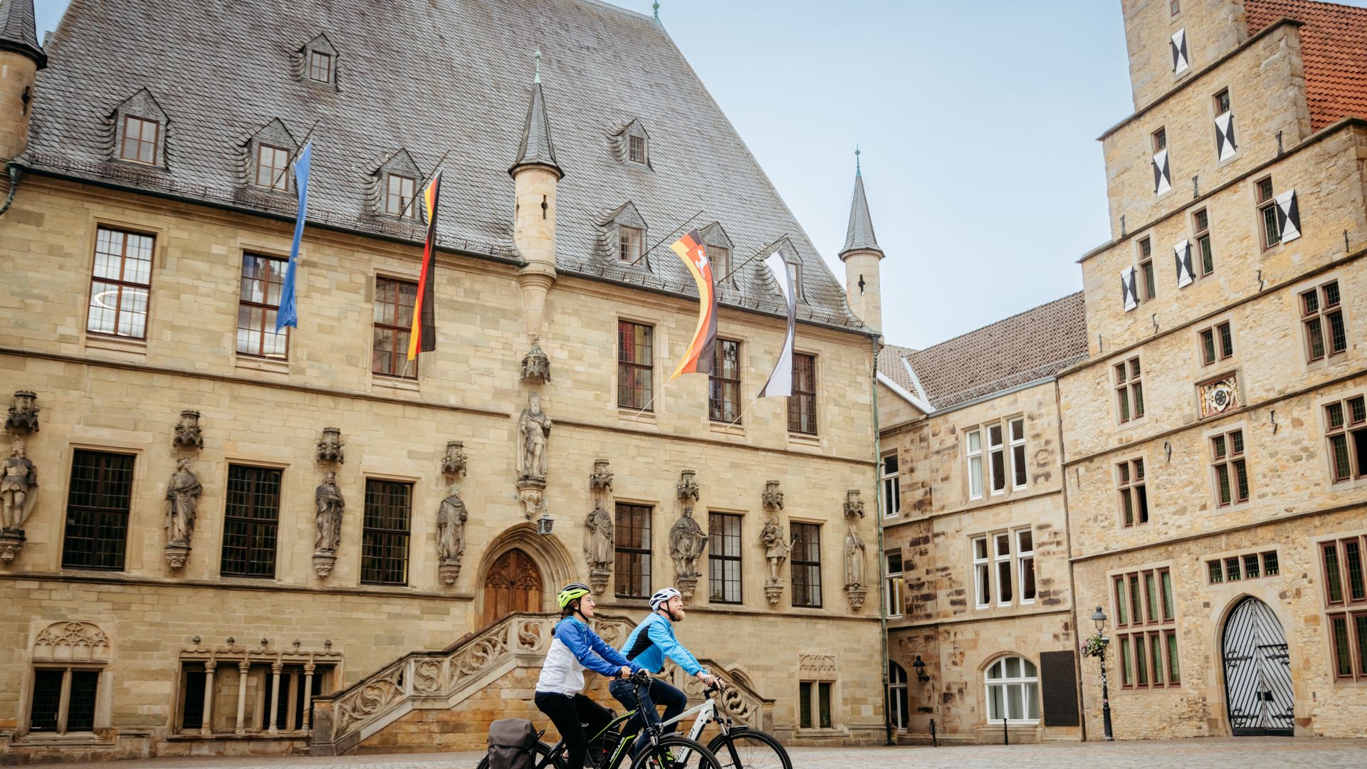 Twee fietsers voor een historisch zandstenen gebouw met beeldhouwwerken.