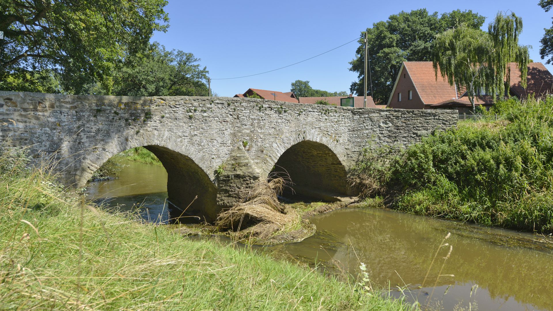 Historische Romeinse brug over de Hunte, omgeven door weiden en een natuurlijk rivierlandschap.