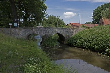 Historische Romeinse brug over de Hunte, ingebed in een vredig rivier- en weidelandschap.