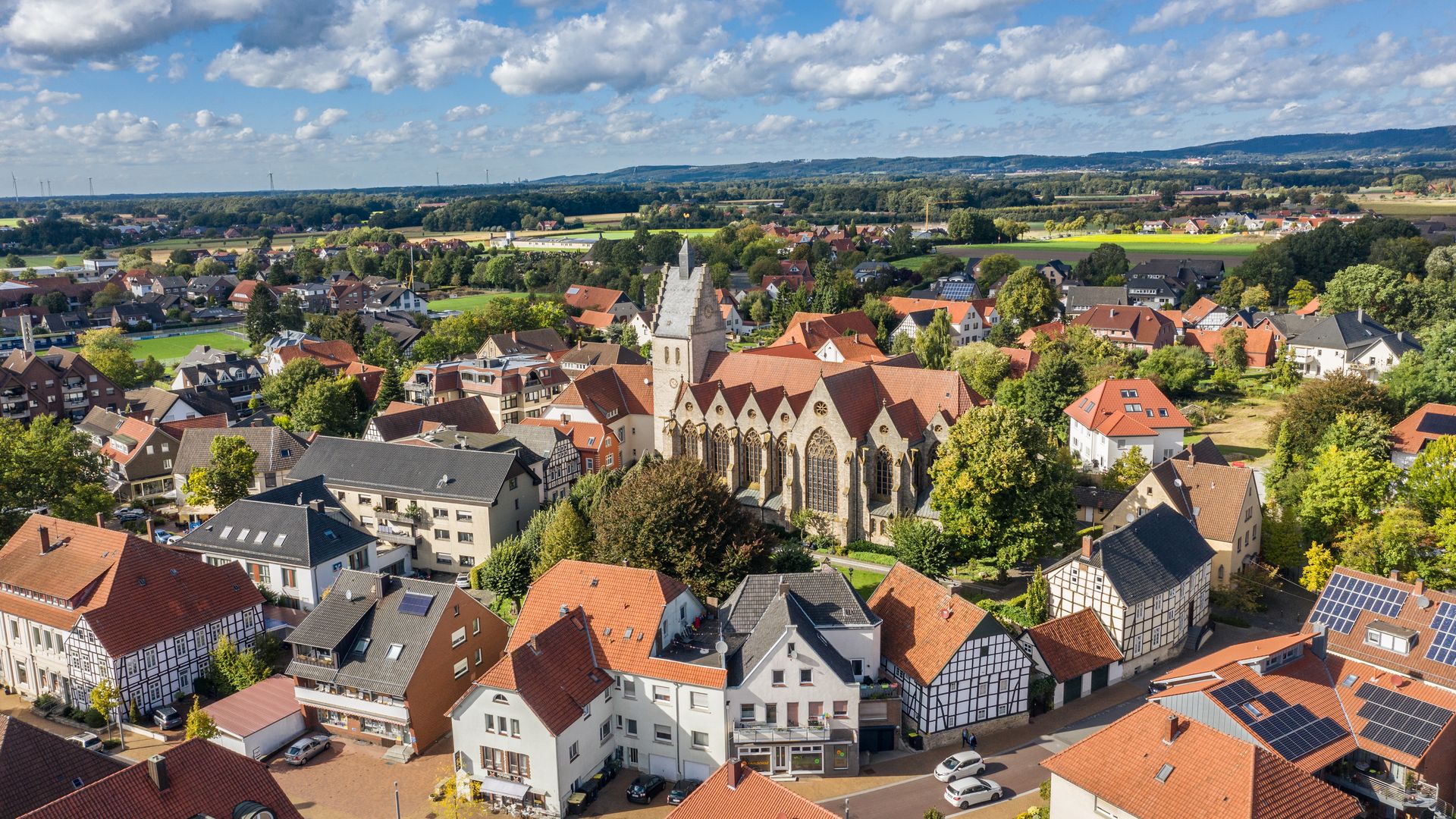 Kerk in het centrum van een rustig dorp, omringd door huizen en een groen landschap.