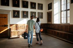 Zwei Personen betrachten Porträtgemälde in einer historischen Kunstgalerie.