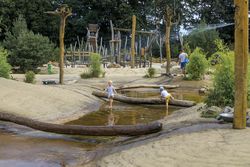 Kinderspielplatz mit Wasserspielbereich, Holzinstallationen und spielenden Kindern.