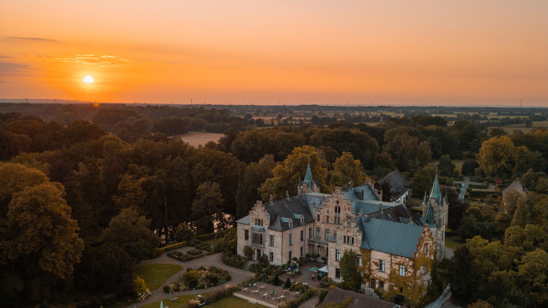 Het kasteel en het tuinlandschap bij zonsondergang tegen de pastelkleurige avondhemel.
