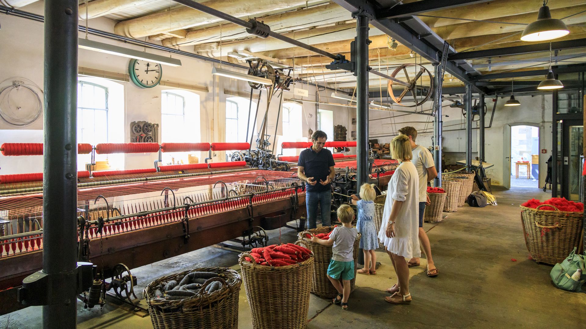 Interieur van het Tuchmachermuseum Bramsche, met historische weefgetouwen, werkmaterialen en bezoekers in de tentoonstellingsruimte.
