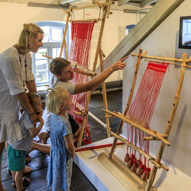 Een gezin bekijkt traditionele weefgetouwen in een museum.